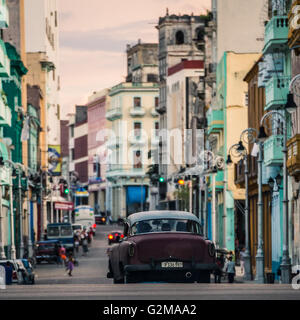 Ein altes Fahrzeug aus den 1950er Jahren reist entfernt von der Kreuzung (und meine Kamera) & durch eine typische Szene in Havanna. Stockfoto