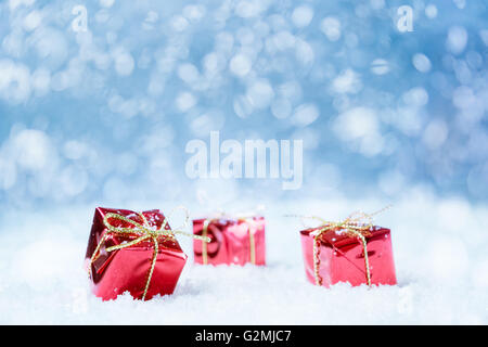 Rote Geschenke auf Schnee mit blauem Hintergrund für eine Grußkarte oder Gutschein, Gutschein. Ausgewählte Fokus, engen Schärfentiefe. Stockfoto