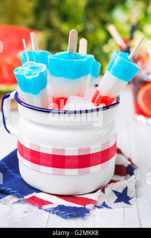 Hausgemachte rot-weiß-blauen Eis am Stiel auf einen Tisch im Freien mit erfrischenden Limonade im Hintergrund. Stockfoto