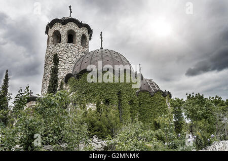 Die alte Kirche mit Efeu auf dem Hintergrund der Gewitterhimmel verwoben. Stockfoto