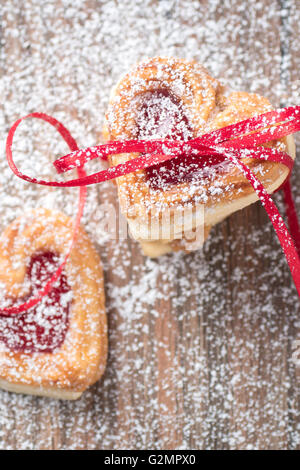 Marmelade, gefüllte Herzkekse mit Schleife und Puderzucker Zucker Closeup. Stockfoto