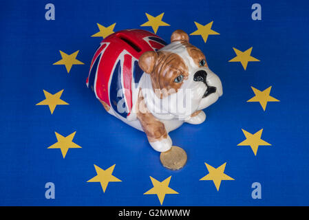 Britische Bulldogge sitzt in EU-Sternen und hält eine Pfote auf ein Pfund-Münze Stockfoto