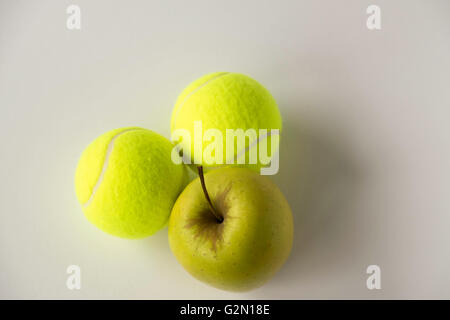 Goldener Apfel mit zwei Tennisbälle auf weißem Hintergrund Stockfoto