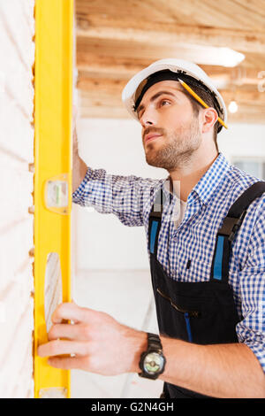 Nahaufnahme eines Bauarbeiters Überprüfung an der Wand im Innenbereich Stockfoto