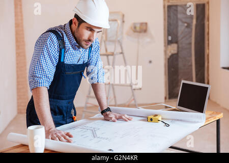 Architekten arbeiten auf Blaupause, Diagramm mit Laptop im Haus Stockfoto