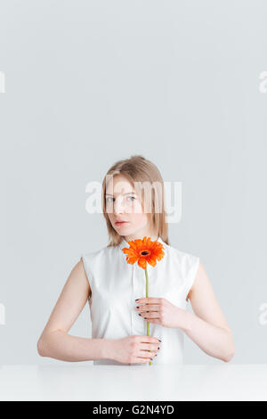 Schönheit-Porträt von attraktiven blonden Frau am Tisch sitzen und, die Blume auf einem weißen Hintergrund isoliert Stockfoto