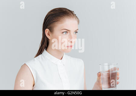 Schönheit-Porträt einer nachdenklichen Frau mit Glas mit Wasser isoliert auf weißem Hintergrund Stockfoto