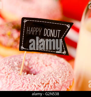 Nahaufnahme von einem Black Flag-förmigen Schild mit dem Text zufrieden Donut-Tag in einem leckeren Donut beschichtet mit rosa Zuckerguss und wh Stockfoto