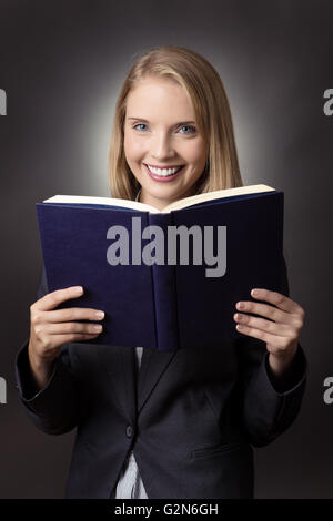 Hübsches junges Modell, der Lust auf lesen hält vor, sie halten das Buch in der Nähe von ihrem Gesicht ganze exp ein geöffnetes Buch blau Stockfoto