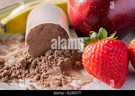Chocolate shake Pulver auf einem Teller mit Äpfeln, Bananen und Erdbeeren und eine Kugel Stockfoto