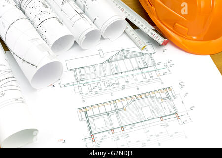 Schutzhelm mit Holzlineal und Blueprint rollt Stockfoto