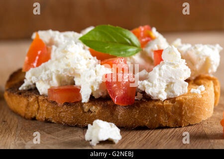 Nahaufnahme eines Bruscheta mit Käse und Tomaten auf hölzernen Hintergrund Stockfoto