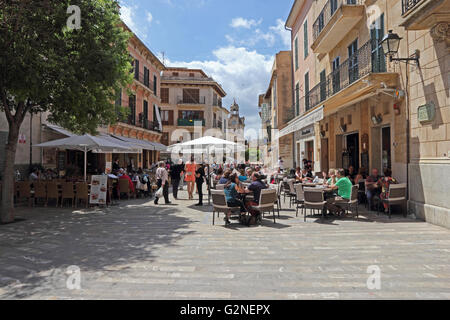 Menschen saßen draußen Cafés in Placa De La Constitucio, Alcudia, Mallorca Stockfoto