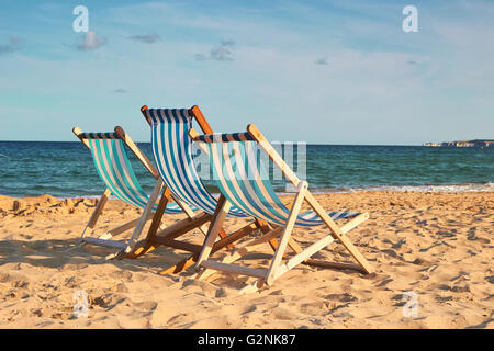 Drei Strandkörbe an einem goldenen Strand mit blauem Himmel, filmischen Blick Stockfoto