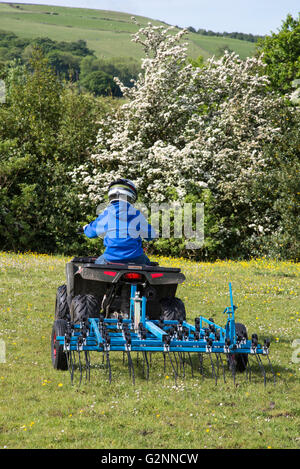 Junge Eggen ein Feld mit seinem Quad-Bike an einem sonnigen Sommertag. Stockfoto