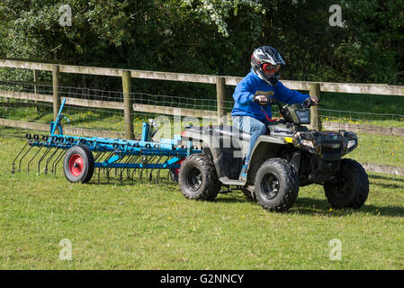 Junge Eggen ein Feld mit seinem Quad-Bike an einem sonnigen Sommertag. Stockfoto