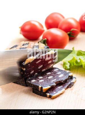 Geschnittene Wurst mit einem Messer auf Holz Hintergrund Stockfoto