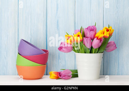 Frische rosa Tulpe Blumen Blumenstrauß und bunten Schalen auf Regal vor Holzwand Stockfoto