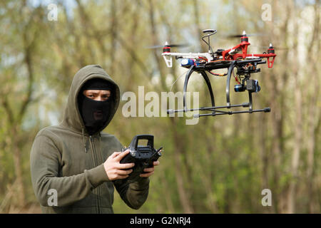 Mann mit Maske, die eine Drohne mit Fernbedienung in Betrieb. Stockfoto