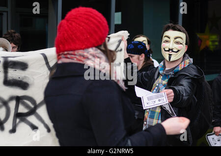 Ein junger Mann trägt eine Guy Fawkes Maske, gleichbedeutend mit der Hacker-Gruppe "Anonymous" Hände eine Broschüre, ein Passant während einer Protestaktion gegen Internet-Gesetzgebung. Belfast 02.11.2012 Stockfoto