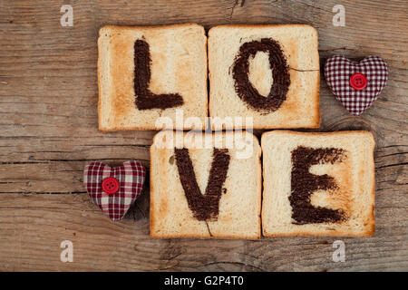 Toastbrot mit das Wort Liebe mit Haselnuss Schokolade verteilt und Tuch Herzen gemalt Stockfoto