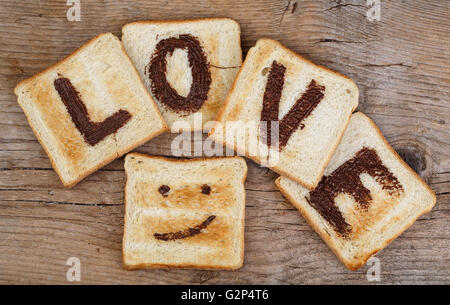 Toastbrot mit das Wort Liebe mit Haselnuss Schokolade verteilt und lächelndes Gesicht gemalt Stockfoto