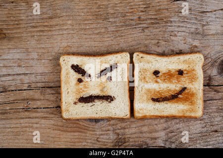 Toastbrot mit glücklich und böse Gesicht gemalt mit Haselnuss Schokolade Verbreitung Stockfoto