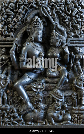 Shiva und Parvati, Orissa, Indien, 12thC des 13. Jahrhunderts. Ein Stein Figur des "Hara-Pārvatī" (Śiva mit Pārvatī auf seinem Schoß sitzen), auch bekannt als Umamahesvaramurti, begleitet von einem Löwen und einem Stier (Nandi) und umgeben von vielen fliegen und ständigen Begleiter. Angezeigt in das britische Museum in Bloomsbury, London, UK Stockfoto