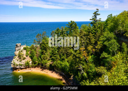 Der Sandsteinturm von Miners Castle zeigt kleine Kiefern auf seinen Simsen über einer dunklen Höhlenöffnung im Pictured Rocks National Lakeshore, Michigan. Stockfoto