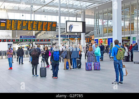 Passagiere mit Koffer Gepäck betrachten Abfahrtstafel an der London Bridge station England UK mit Ticket Barrieren & Züge über Stockfoto