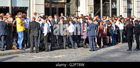 Überwiegend Büroangestellte, die nach der Arbeit in der City of London UK auf der Straße stehen und sich unterhalten und trinken Stockfoto