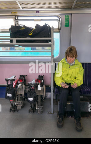 Eine ältere Frau reist per Zug mit Brompton Fahrräder und Gepäck in einer Kutsche, die Fahrräder zu transportieren. Stockfoto