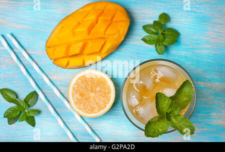 Mango-Eis-Tee mit Minze im Glas auf blauen hölzernen Hintergrund (Draufsicht) Stockfoto