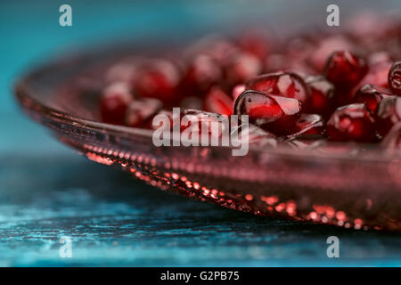 Frische helle rote Granatapfel Grenadine Obst Samen auf blauen hölzernen Hintergrund stilleben Studio gedreht Stockfoto