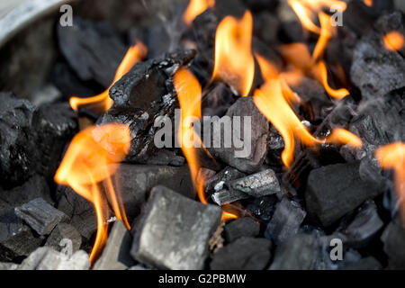 Holzkohle zum Grillen mit leuchtend orangefarbenen Flammen entzünden Stockfoto