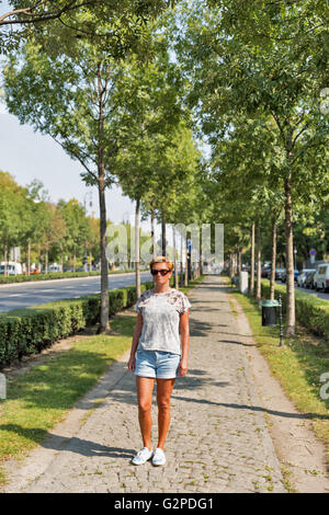 Kaukasische mittleren Alters gebräunte Frau Spaziergang entlang der Andrassy Avenue in Budapest, Ungarn. Es ist eine 2,5 km lange Allee, die Stockfoto