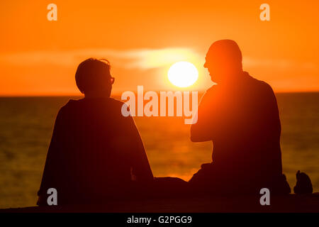 Aberystwyth Wales UK, Feiertag Mittwoch, 1. Juni 2016 UK Wetter: ein paar sitzen in der Silhouette an Aberystwyth Promenade als hinter ihnen die Sonnen geht dramatisch über Cardigan Bay am Meer am Aberystwyth an der Westküste von Wales.  Das Wetter war schön und warm an der Westküste, in scharfem Kontrast zu den Stürmen und Regen in London erlebt und östliche Regionen Bildnachweis: Keith Morris / Alamy Live News Stockfoto