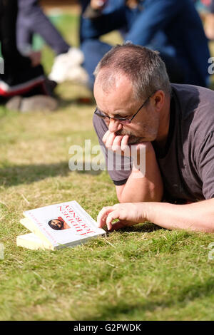 Hay-Festival, Wales, UK - Donnerstag, 2. Juni 2016 - sieht ein Besucher auf dem Cover seines neuen Buches auf dem Rasen an der Hay-Festival in der Nachmittagssonne. Stockfoto