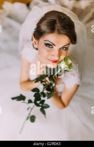 Zarte Rose in den Händen der jungen Mädchen gekleidet weißes Brautkleid Stockfoto