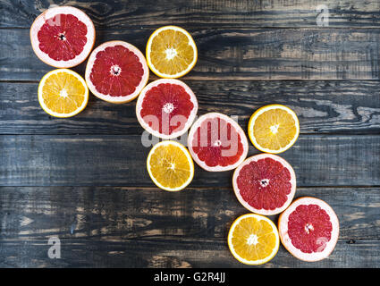 Diagonalen Reihe roter Grapefruit Scheiben mit Orangen auf dunkle strukturierte rustikalen Holztisch. Draufsicht mit Textfreiraum Stockfoto