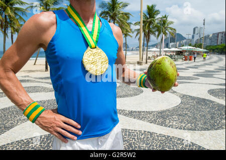 Goldmedaille Athlet stehend mit grünen Kokosnuss Coco Gelado auf der Promenade am Strand der Copacabana, Rio De Janeiro, Brasilien Stockfoto