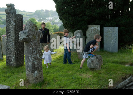 Kinder, die außerhalb von St. Neot Cornwall Großbritannien spielen. Alte keltische Kreuze im Kirchenhof. 2016 HOMER SYKES, 2010er Jahre Stockfoto