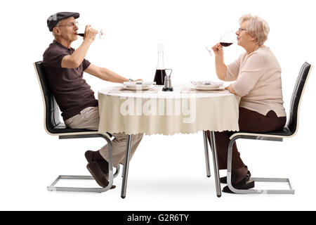 Älterer Mann und Frau trinken Rotwein und sitzt auf einem Datum isoliert auf weißem Hintergrund Stockfoto