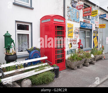 Gebäude mit Zinn Werbeschilder, darunter eine K6 Telefonzelle in Horseleap, County Offaly, Südirland bedeckt. Stockfoto