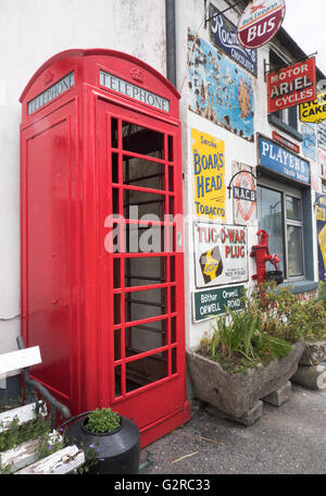 Gebäude mit Zinn Werbeschilder, darunter eine K6 Telefonzelle in Horseleap, County Offaly, Südirland bedeckt. Stockfoto