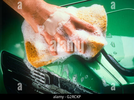 A mans Händewaschen ein leuchtendes grünes Auto. Stockfoto