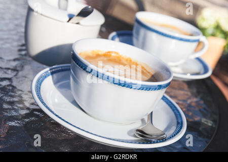 Zwei Tassen Cappuccino stehen auf Glastisch im Straßencafé, Nahaufnahme Foto mit selektiven Fokus Stockfoto