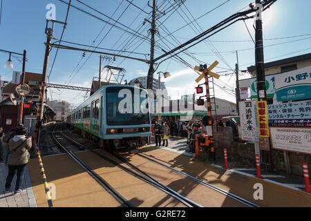 Ein Zug auf der Enoden-Bahnlinie an einer Kreuzung in der Nähe der Enoshima-Station, Kanagawa, Japan. Stockfoto