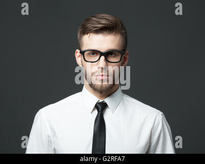 Porträt von schön ernst junger Geschäftsmann gegen dunkelgrauen Hintergrund stehend. Stockfoto