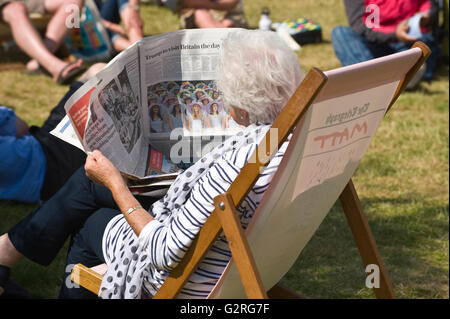 Ältere Dame lesen Zeitung setzte sich im Liegestuhl auf der Wiese bei Hay Festival 2016 Stockfoto